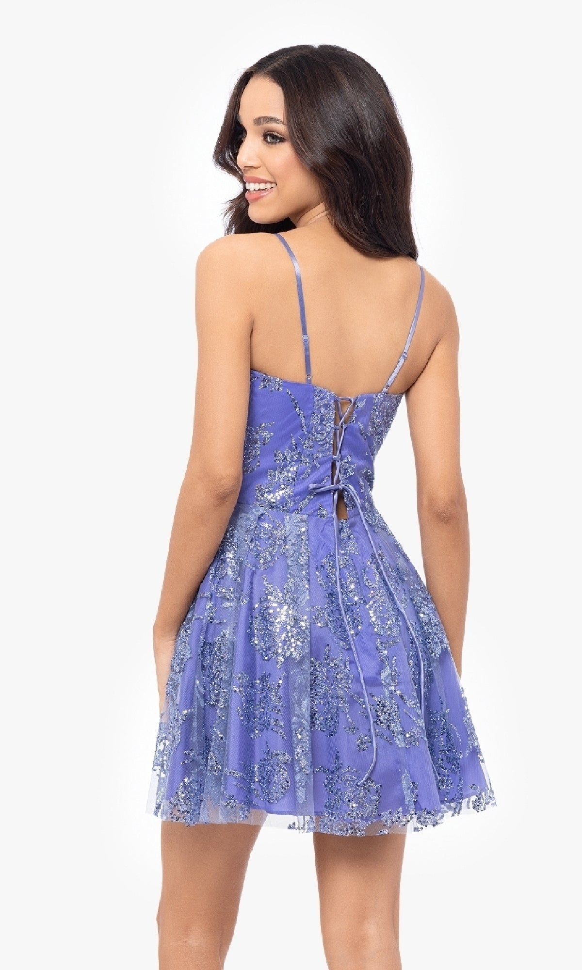 Woman wears the Short Periwinkle Hoco Dress: Blondie Nites 5017BN, featuring silver floral patterns and a lace-up back, smiling as she faces away from the camera.